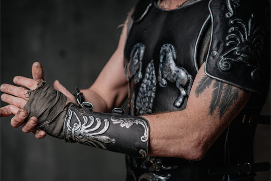Close view of a black Maximus gladiator cuirass, decorated pauldron, and matching leather bracer