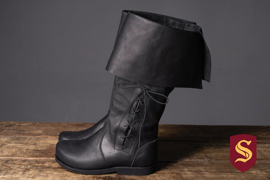 Pair of black leather Ranger boots with wide folded cuffs and side lacing on a wooden surface