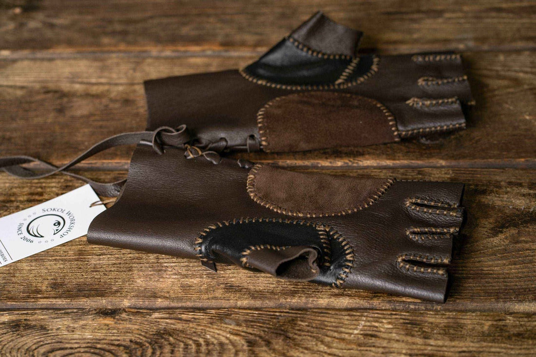 Pair of brown and black fingerless Aragorn Strider leather gloves displayed on a wooden table