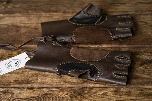 Pair of brown and black fingerless Aragorn Strider leather gloves displayed on a wooden table