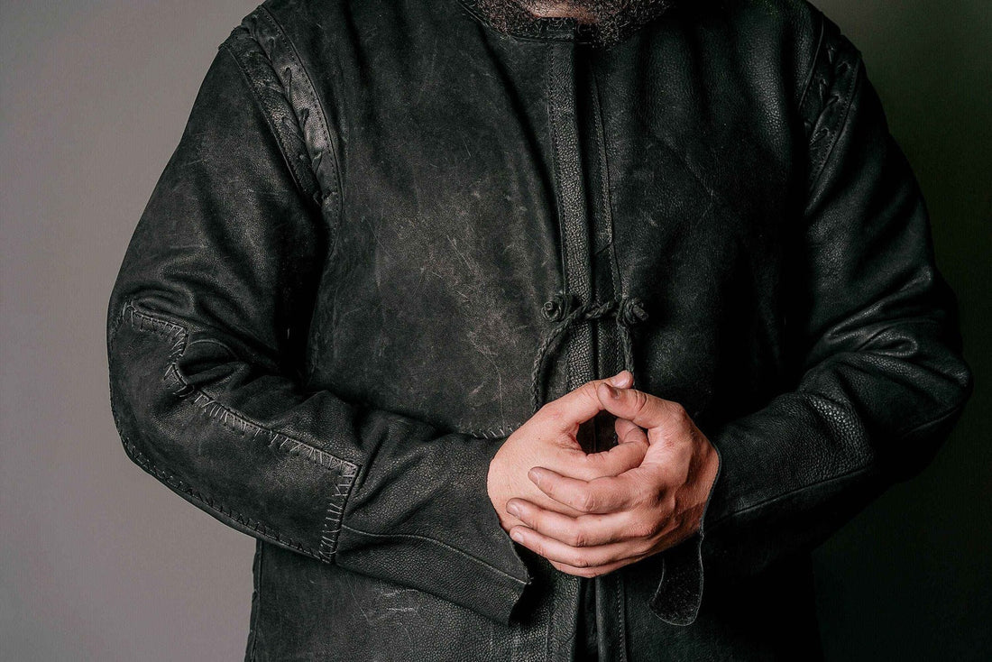 Close view of a weathered black leather fantasy duster with stitched sleeves and front ties