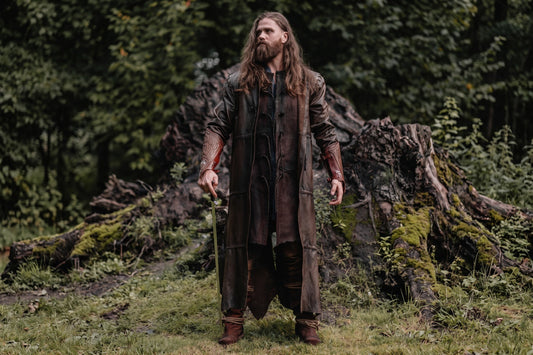 Model wearing a long brown leather Aragorn duster costume outdoors with matching bracers