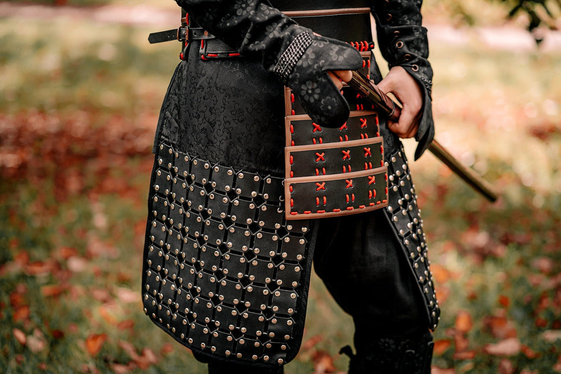 Close view of black samurai-inspired skirt armor with metal fasteners and red lacing outdoors