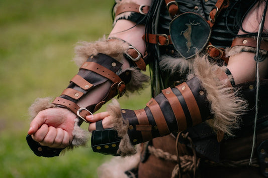 Brown and black leather bracers with fur trim being fastened outdoors