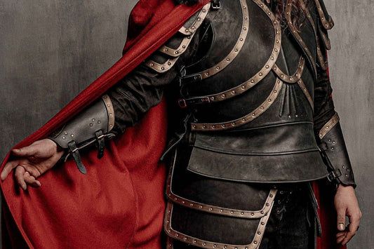 Close view of a red Dracula cloak beside a dark cuirass, bronze-colored trim, hip panels, and bracers