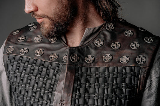 Close view of a model wearing dark woven leather body armor with round metal studs