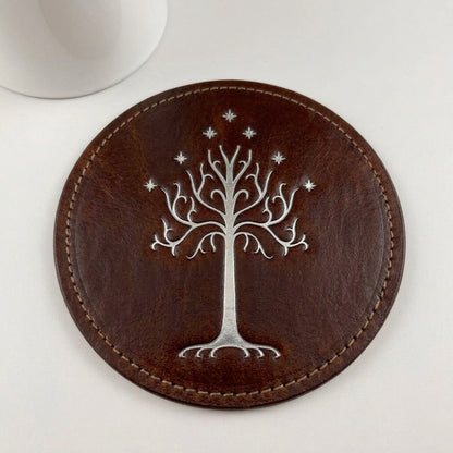 Close-up of a round brown cowhide leather coaster with silver White Tree embossing
