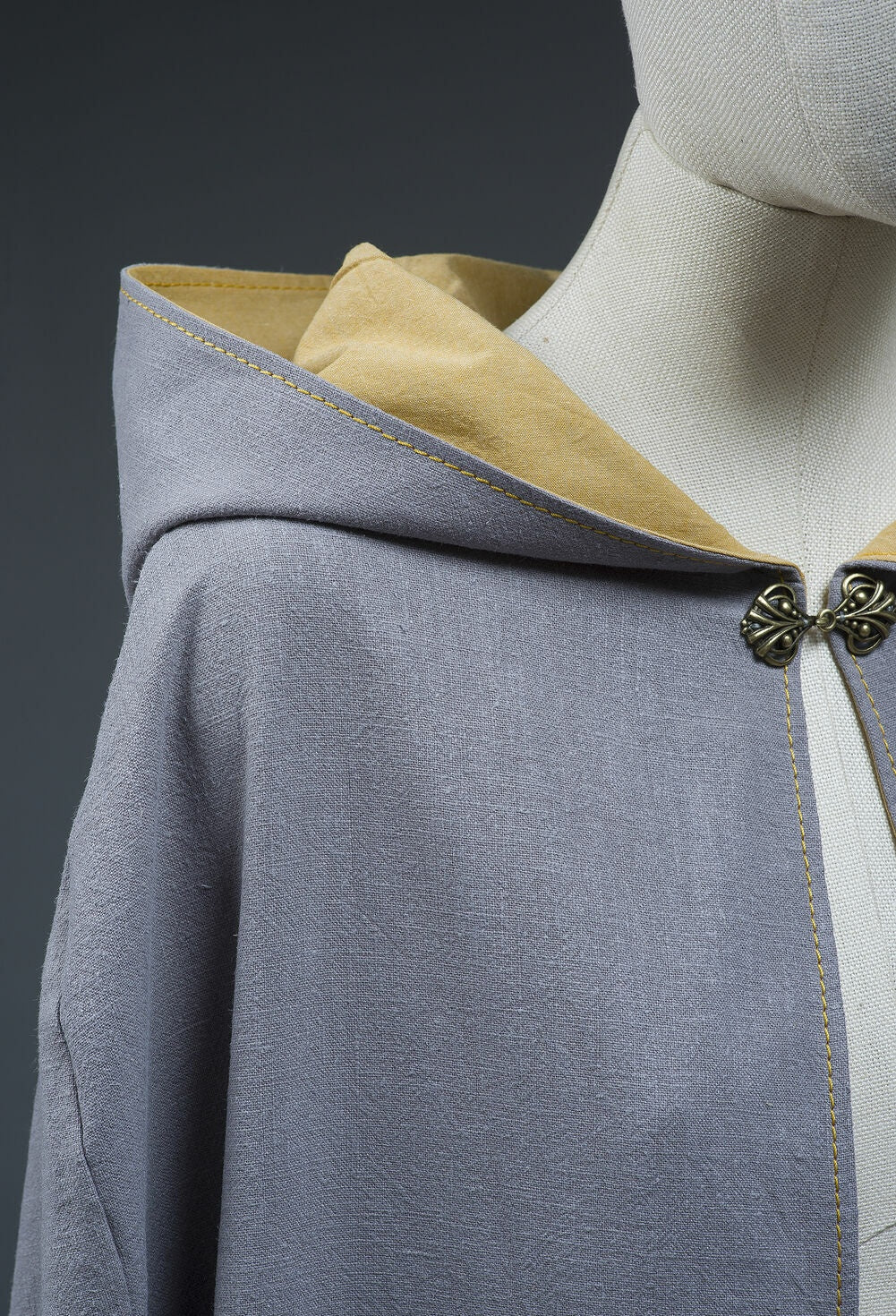Close-up of metal clasp, hood, and contrasting lining on cotton cloak