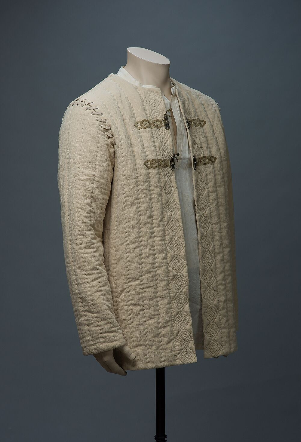 Natural beige medieval jacket with leather trim, angled view