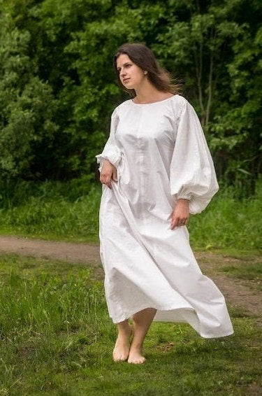 a man in a white dress holding a white frisbee 